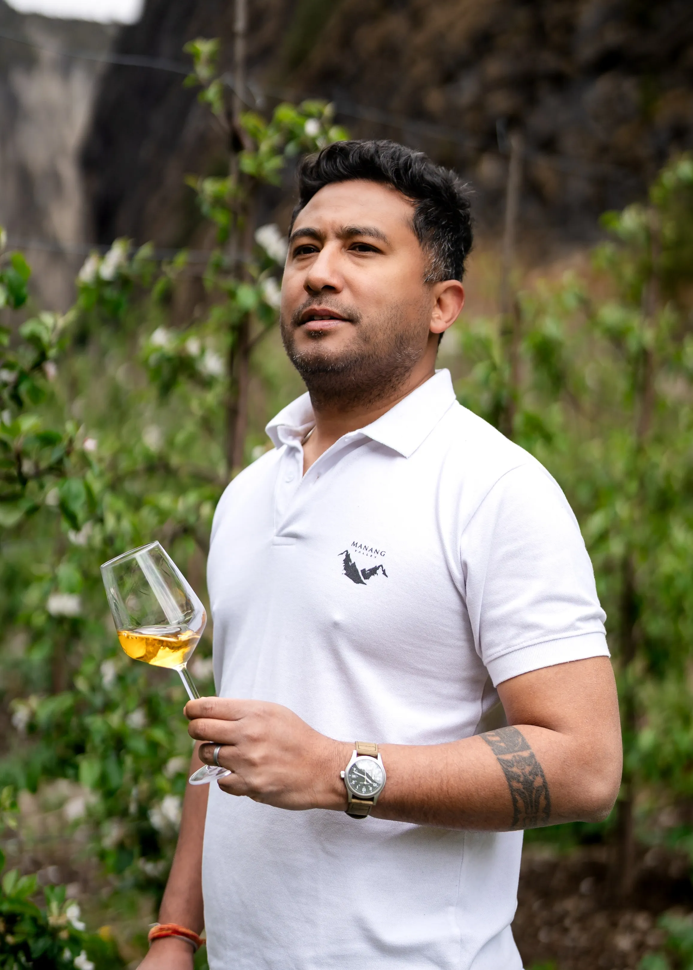Ashraya Ranjitkar, Managing Partner and Production Director, holding a glass of apple wine in the orchard