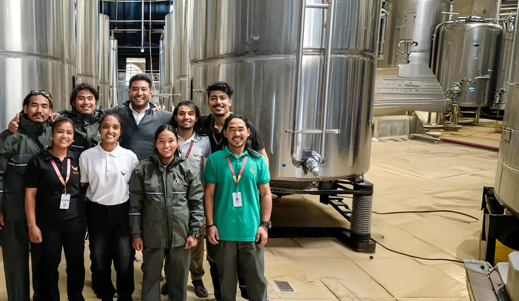 The Manang Valley winery team standing among the stainless-steel tanks