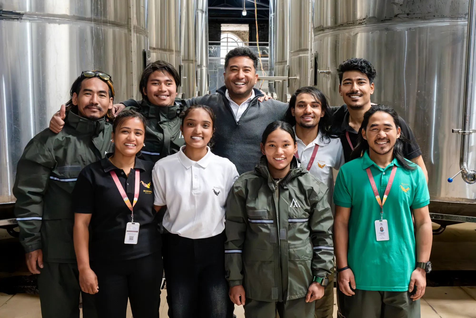 Members of the Manang Valley team standing together among the steel tanks at the winery
