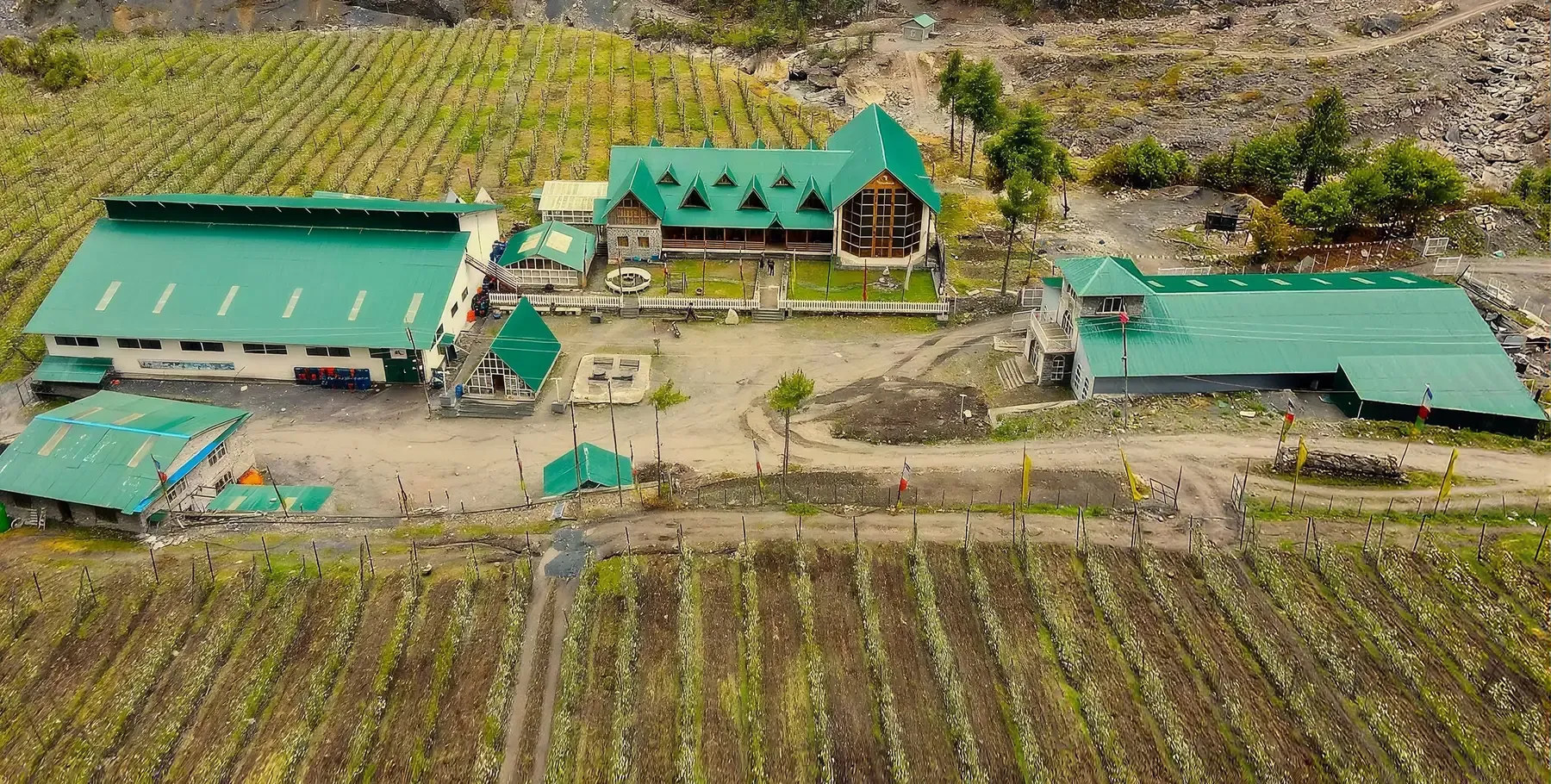 Aerial view of the Manang Valley winery, its green-roofed buildings surrounded by rows of apple trees